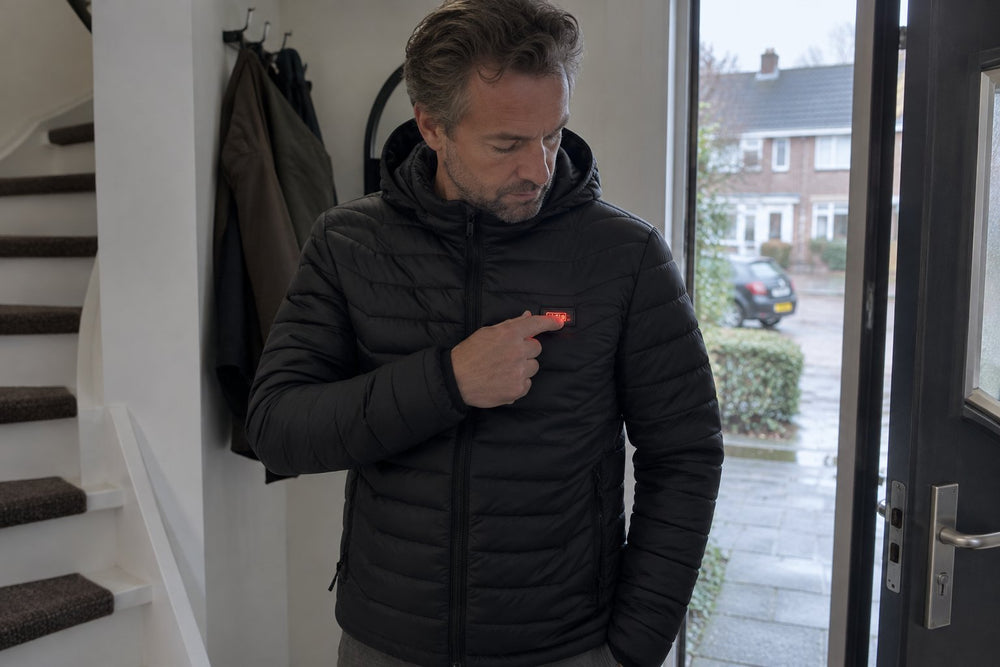 Man zet de verwarming van zijn jas aan bij de voordeur