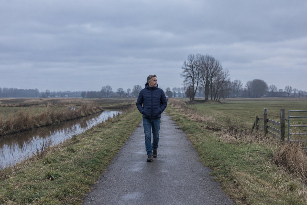 Man wandelt in verwarmde jas door de Nederlandse polder